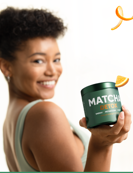 Frau hält Matcha Detox Dose mit Orangenzeste — Lifestyle-Moment